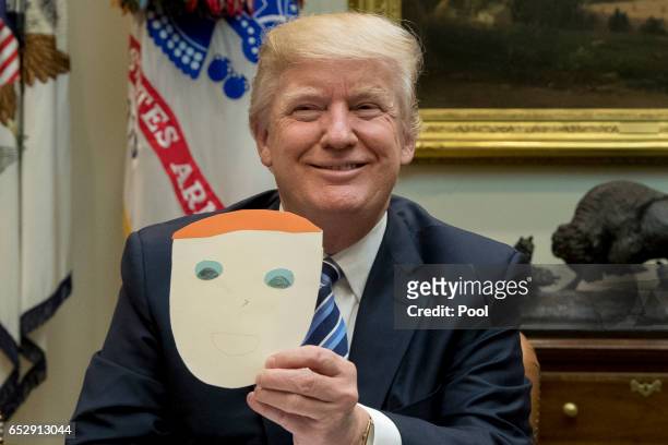 President Donald Trump holds up a note and drawing depicting him that was created by the child of Greg Knox of Ohio, during a meeting on healthcare...