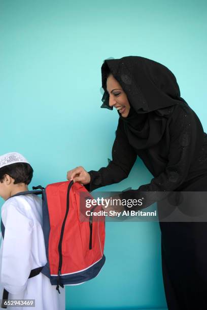 a mother fixes her sons school bag. - parental guidance stock pictures, royalty-free photos & images