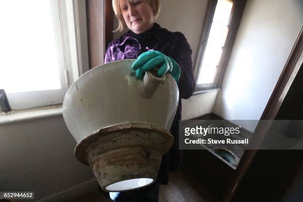 Elizabeth Nelson-Raffael holds the bowl, her pinky finger is where the part of the bowl where water would have entered through a lead pipe....