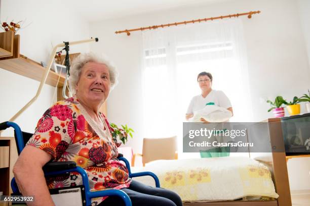 cuidador que socializar con mujer mayor mientras que limpia su cuarto - residential care fotografías e imágenes de stock