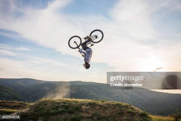skillful man on bicycle performing backflip in nature. - backflipping stock pictures, royalty-free photos & images