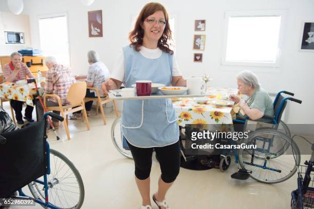 caregiver taking lunch to a senior woman in the room - residential care stock pictures, royalty-free photos & images