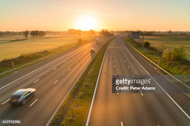 traffic on a motorway at sunrise, uk - autostrada foto e immagini stock