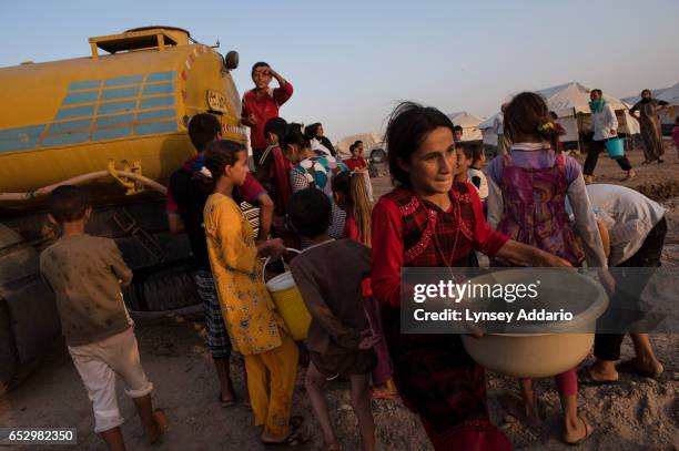 Iraqi Yazidi families fight to take water from a government water truck at the Bajid Kandal camp near the Iraqi border with Syria, in Northern Iraq,...