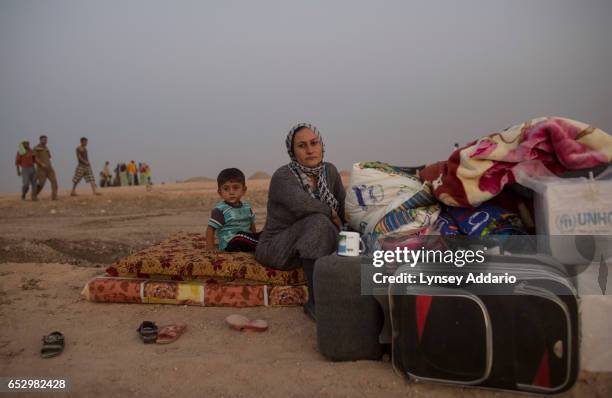 Iraqi Yazidi woman Baral Amr sits with her two children and her belongings shortly after arriving at the Bajid Kandal camp near the Syrian border, in...