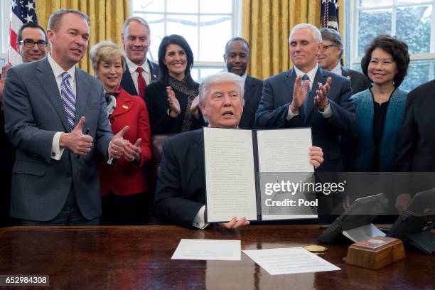 President Donald Trump shows an executive order entitled, 'Comprehensive Plan for Reorganizing the Executive Branch', after signing it beside members...