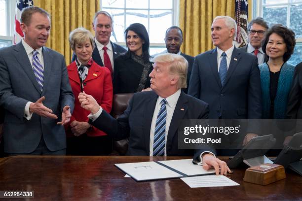 President Donald Trump hands his pen to Director of the Office of Management and Budget Mick Mulvaney , after signing an executive order entitled,...