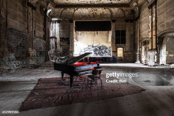 old piano with red light of a flashlight, in the hall of an old party location (in berlin) - lost stock-fotos und bilder