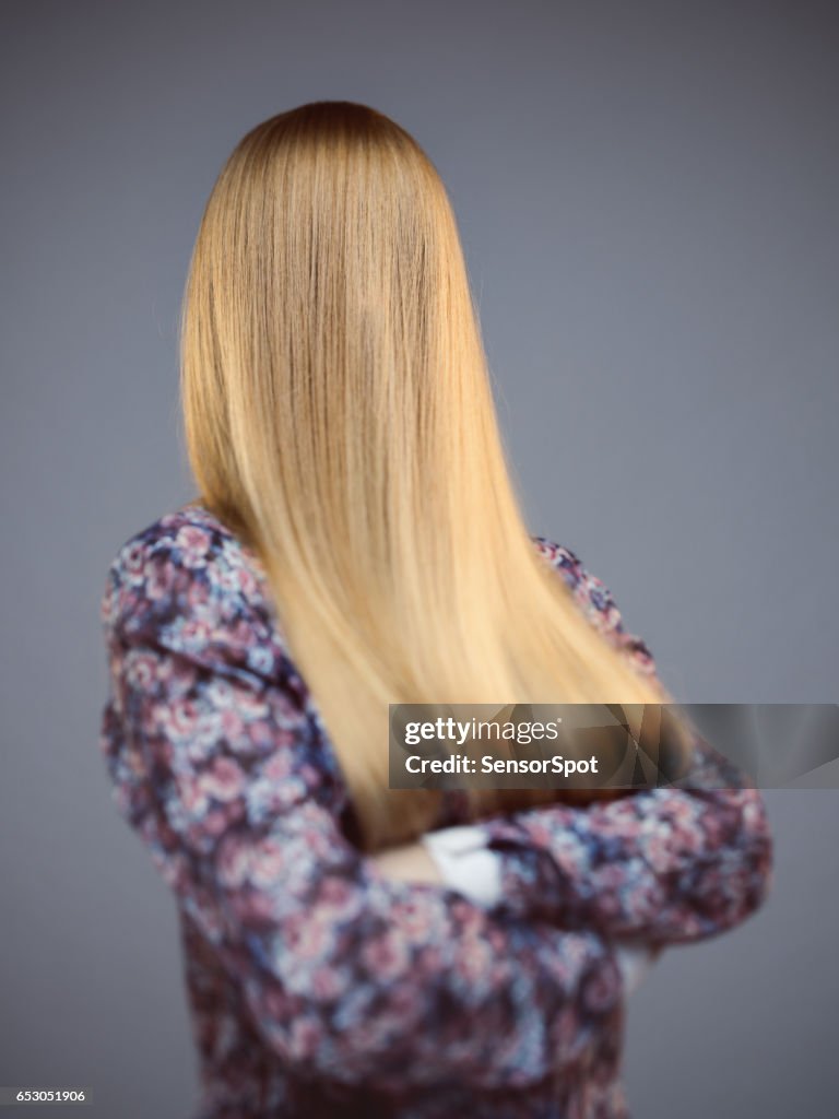 Jeune femme avec le visage couvert de longs cheveux blonds