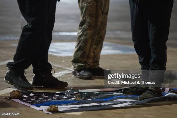 Demonstrators trample on an American flag that symbolizes support for law enforcement as they protests outside the Ferguson Market and Liquor on...