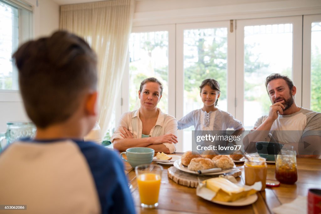 Young family having pleasant conversation during breakfast in the dining room