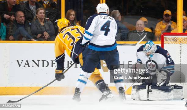 Connor Hellebuyck of the Winnipeg Jets makes the save against Colin Wilson of the Nashville Predators as Paul Postma defends during an NHL game at...