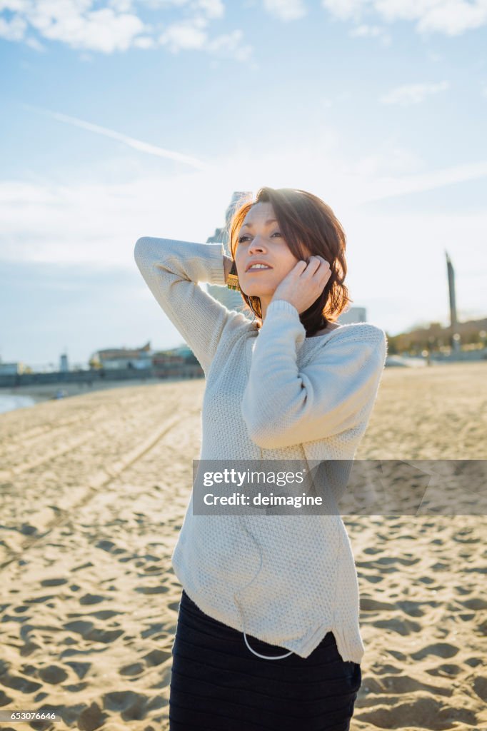 Young woman listening music with headphone at the beach