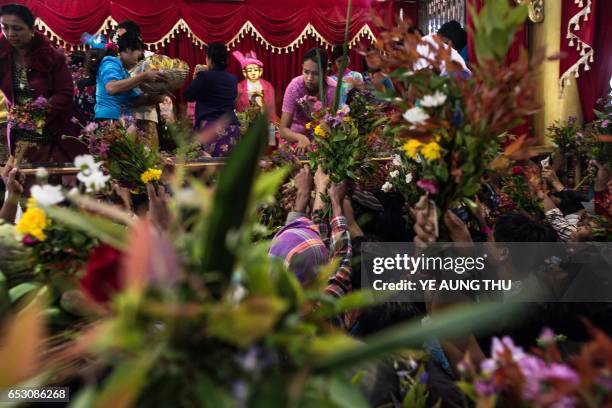 In this photo taken on March 7 devotees clutch flower arrangements and other offerings inside shrine in Shwe Ku Ni village as they participate in the...