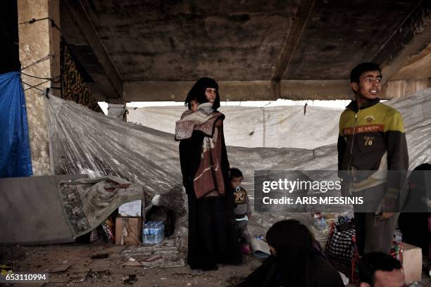 Displaced residents of the Iraqi city of Mosul gather at an empty building where they are taking shelter as they wait for space at the Hamam al- Alil...