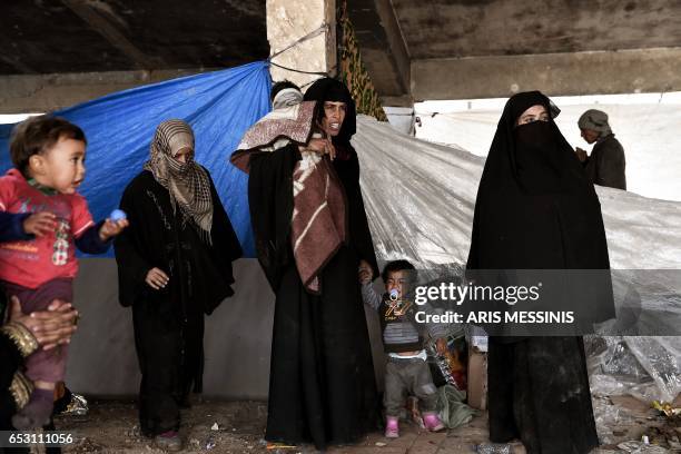 Displaced residents of the Iraqi city of Mosul gather at an empty building where they are taking shelter as they wait for space at the Hamam al- Alil...