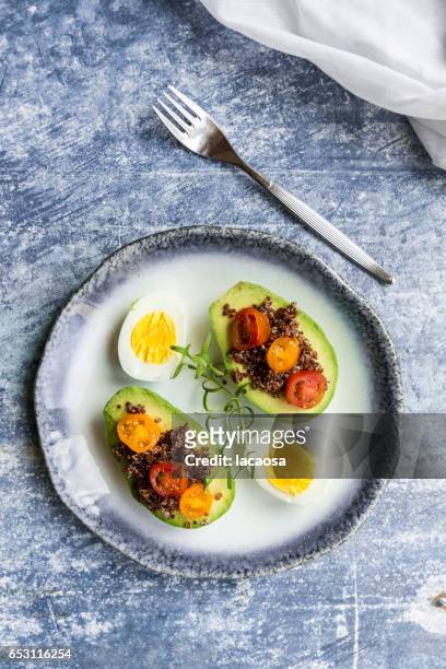 sliced avocado filled with red quinoa, tomatoes and eggs - lacaosa stock-fotos und bilder