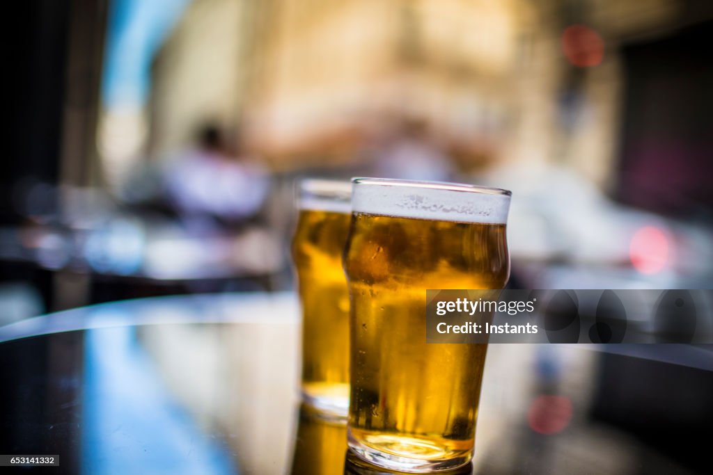 Zwei Gläser blondes Bier auf einem Tisch, auf einem Bürgersteig Paris Café Bar erschossen.