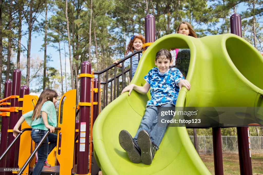 Multi-ethnic elementary school children playing on playground at park.