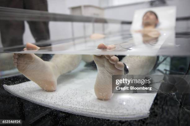 Researcher, wearing active marker motion sensors and electrodes for an electroencephalogram, lies in a tank of water while conducting bathing tests...