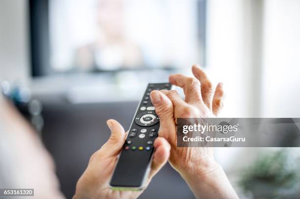 close up hands of senior woman using tv remote control - só uma mulher idosa imagens e fotografias de stock