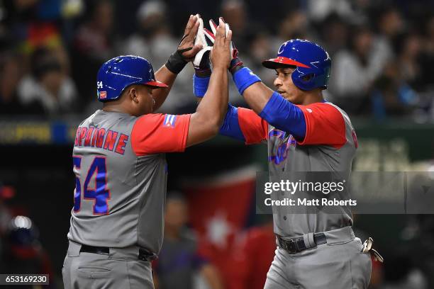 Infielder Yurisbel Gracial of Cuba high fives with Outfielder Alfredo Despaigne after hitting a two run homerun in the top of the second inning...