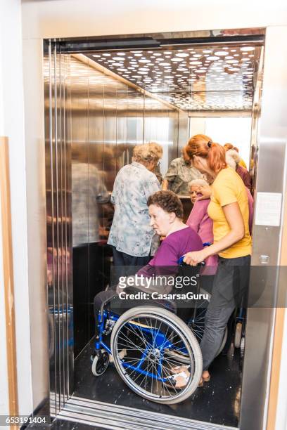 verzorger help senioren bij het verpleeghuis te staan in de lift - crowded elevator stockfoto's en -beelden