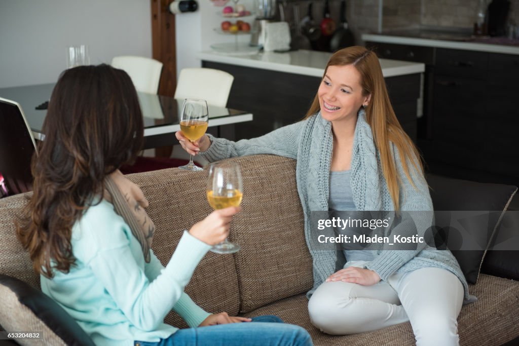 Twee vrouwen zittend op een bank en drinken van wijn