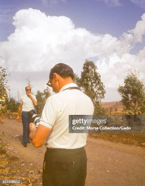 Western tourists visiting war remnant sites in the Golan Heights, Israel, November, 1967. Man in foreground adjusting his camera, while another man...