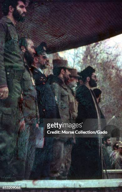 President Ali Khamenei standing center stage among a row of military leaders and Islamic clerics at a rally in Iran, March, 1983. Extensive damage on...