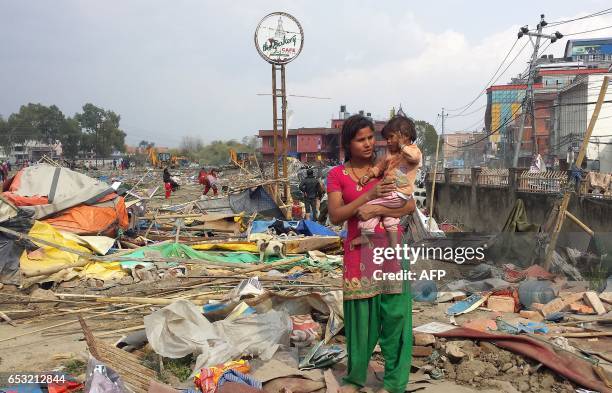 Apsana Tamang carries her one-year-old baby in the remains of a makeshift camp for people displaced by the 2015 earthquake after it was demolished by...