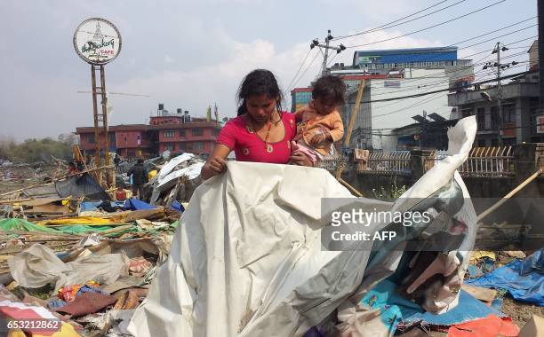 Apsana Tamang carries her one-year-old baby in the remains of a makeshift camp for people displaced by the 2015 earthquake after it was demolished by...