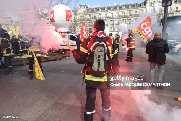 An unionist of the General Confederation of Labour holds a flare during a demonstration of French firefighters against staff reduction on the place...