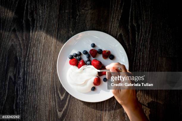 close up of woman hands with yogurt and berries on table - yogurt fotografías e imágenes de stock