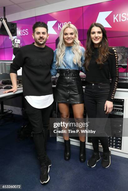 Louisa Johnson poses for photo with Kiss presenters Alex Mansuroglu and Andrea Zara during a visit to the Kiss FM studio on March 14, 2017 in London,...