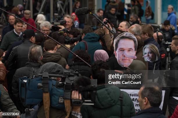 An anti-war protester holds a placard near Dutch Prime Minister Mark Rutte as he talks to journalists while campaigning ahead of tomorrow's general...
