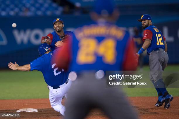 Alcides Escobar of Team Venezuela turns a double play as Rob Segedin of Team Italy slides into second base during Game 6 of Pool D of the 2017 World...