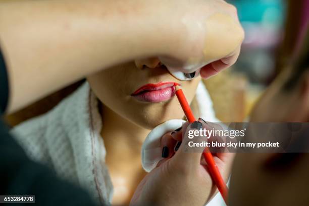 a young woman having her lips painted by a make-up artist. - konturstift stock-fotos und bilder