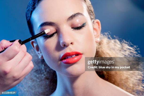 a make-up artist applying glossy eight hour cream to the eyelids of a model. - maquillaje para ojos fotografías e imágenes de stock