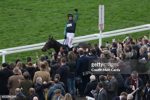 Racegoers cheer as the winner of the second race Altior ridden by Nico de Boinville passes them as they watch the racing at the Cheltenham Racecourse...