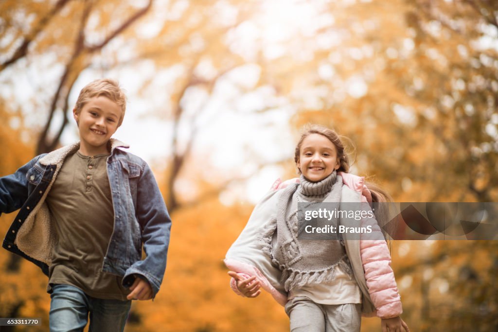 Happy children running in autumn day at the park.