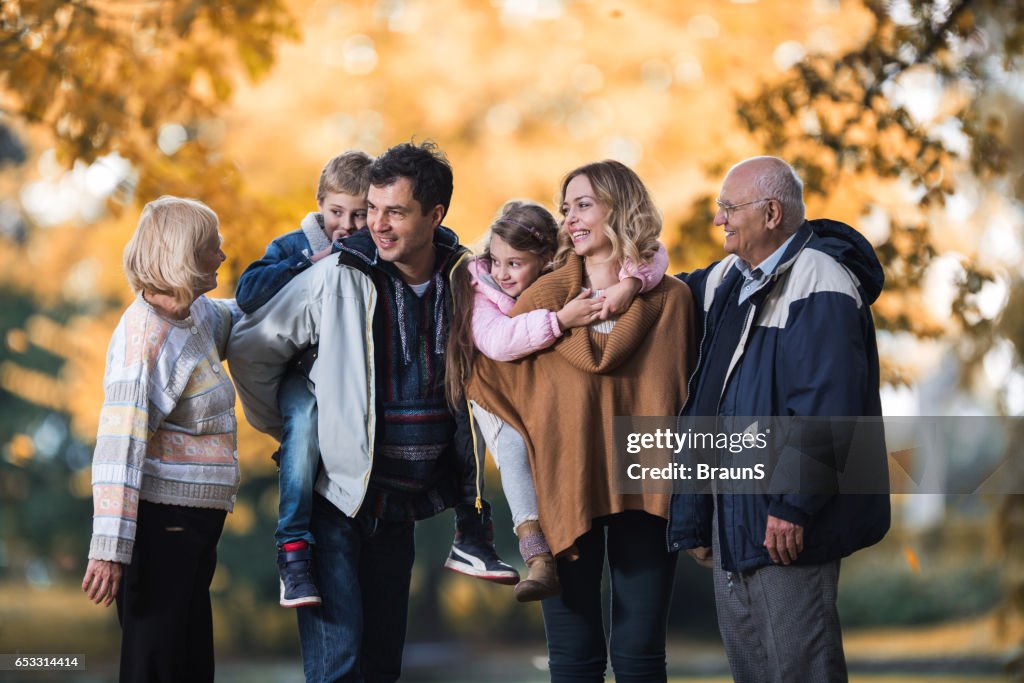 Smiling multi-generation family talking during autumn day in nature.