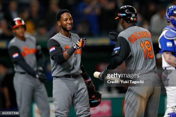 Didi Grgorious of Team Netherlands is greeted by teammate Jurickson Profar after hitting a sacrifice fly in the eighth inning during Game 3 of Pool E...