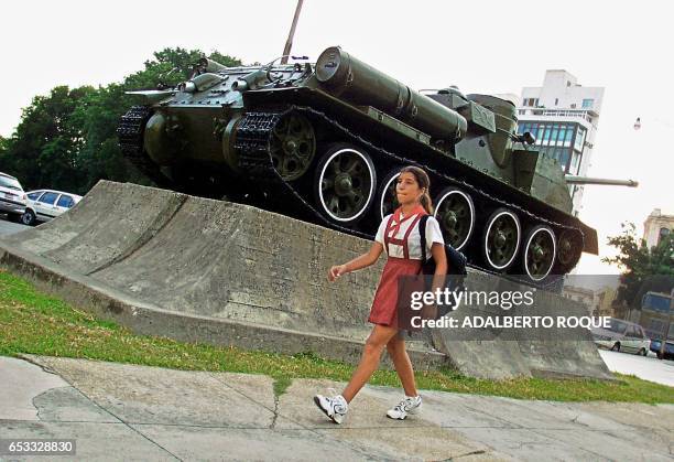 Young girl walks to school on in Cuba 03 September 2001. Una escolar pasa frente a un tanque de guerra expuesto en un museo local el 03 de setiembre...