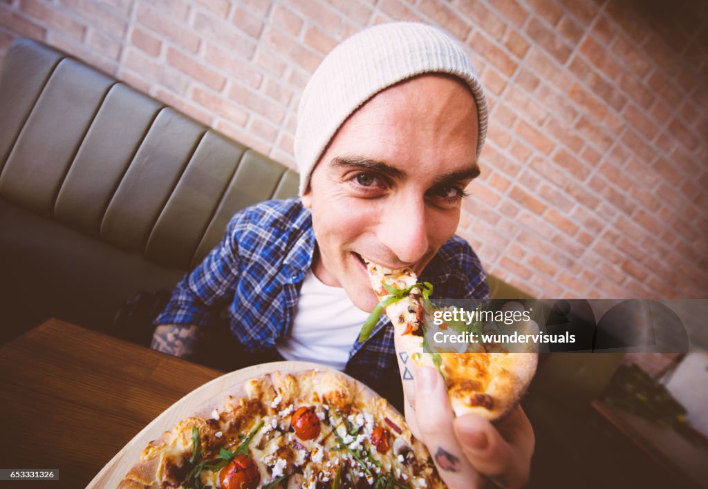 Shot of young man biting a slice of pizza