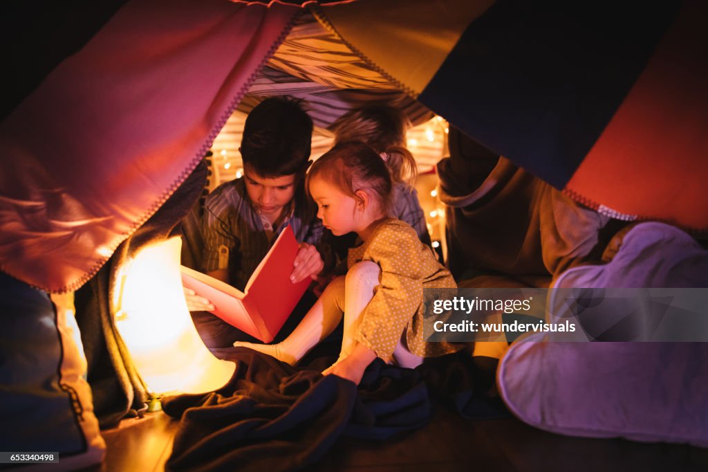 Kinderen lezen een verhaal in deken fort bij nacht
