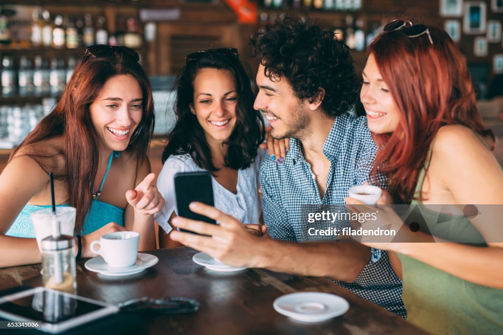 Friends using a smart phone at the cafe