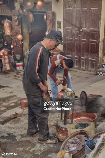 Man polishing a copper pot at a copper workshop in the medina of Fez in Morocco, Africa.