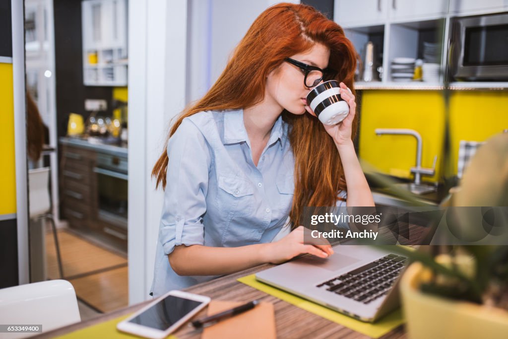 Junge schöne Frau Kaffee trinken und Surfen im Internet auf ihrem Laptop. Morgen-Konzept.