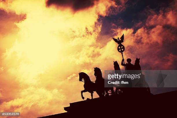 the famous quadriga statue on the brandenburg gate in berlin - dramatic sky - brandenburg stock pictures, royalty-free photos & images